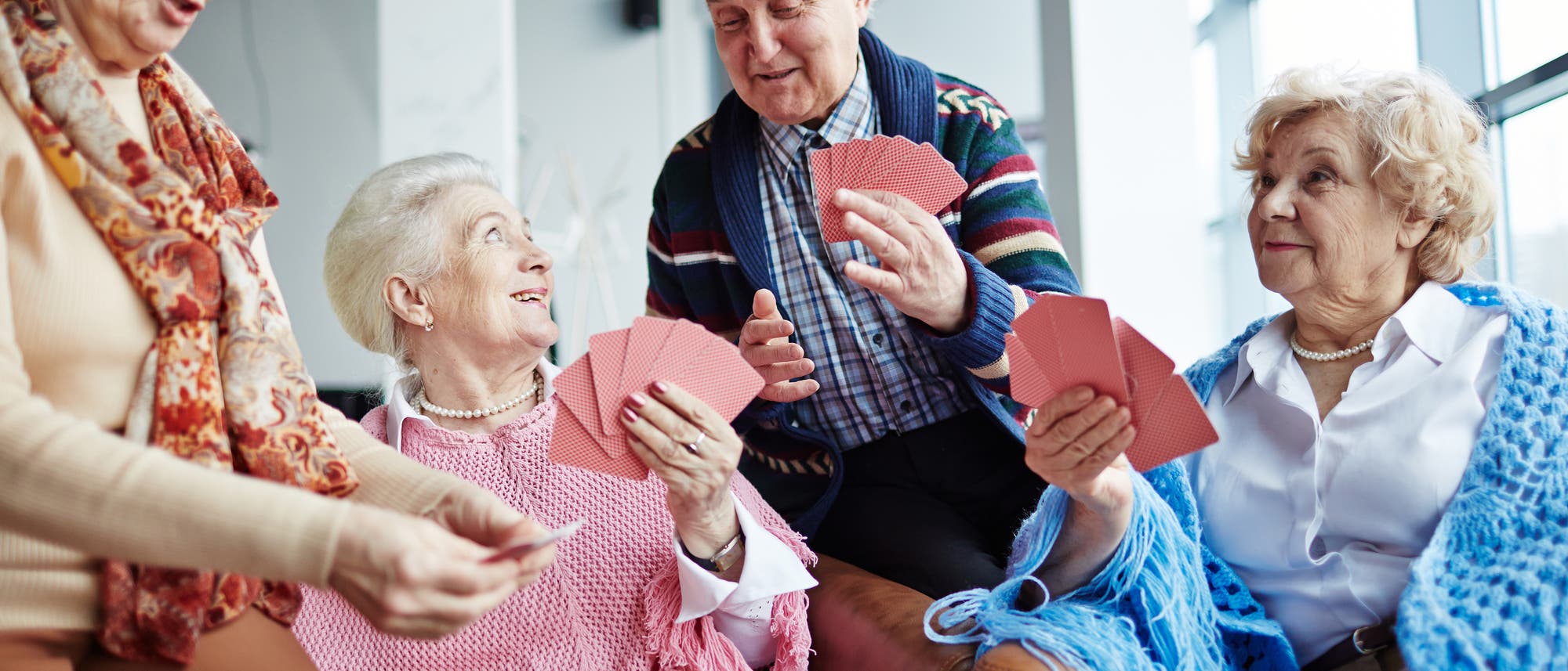Seniorinnen spielen mit altem Herrn Karten