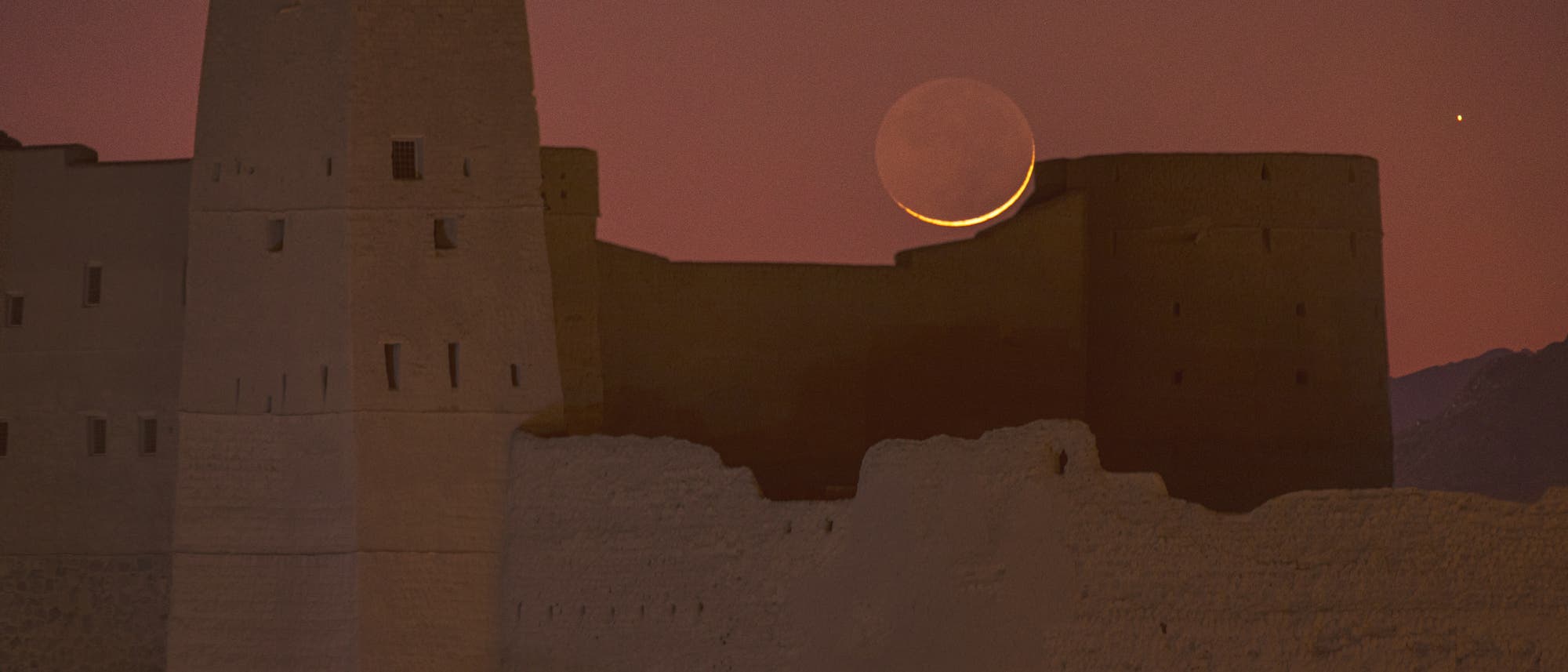 Mond und Saturn über der Festung von Bahla in Oman