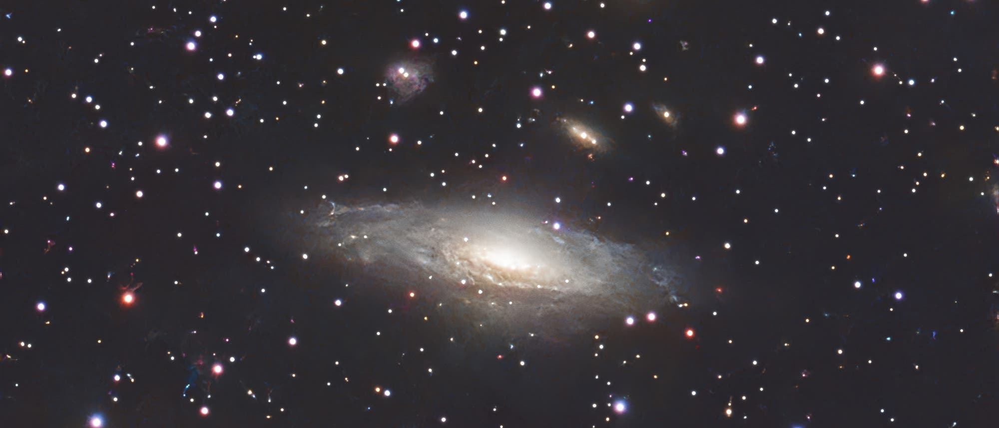 Eine detaillierte Aufnahme des Weltraums zeigt eine Spiralgalaxie im Zentrum, umgeben von zahlreichen leuchtenden Sternen und kleineren Galaxien. Die Spiralgalaxie hat einen hellen Kern und spiralförmige Arme, die von einem diffusen Licht umgeben sind. Der Hintergrund ist tiefschwarz, was die Helligkeit der Sterne und Galaxien hervorhebt. Dieses astronomische Bild veranschaulicht die Weite und Vielfalt des Universums. Eine detaillierte Aufnahme des Weltraums zeigt eine Spiralgalaxie im Zentrum, umgeben von zahlreichen leuchtenden Sternen und kleineren Galaxien. Die Spiralgalaxie hat einen hellen Kern und spiralförmige Arme, die von einem diffusen Licht umgeben sind. Der Hintergrund ist tiefschwarz, was die Helligkeit der Sterne und Galaxien hervorhebt. Dieses astronomische Bild veranschaulicht die Weite und Vielfalt des Universums.