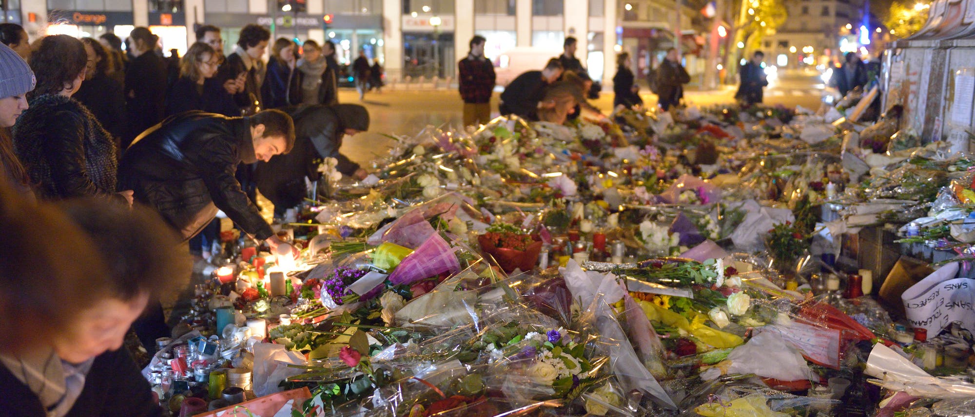 Duzende Menschen legen Blumen am Bataclan in Paris nieder, wo ein terroristischer Angriff eine große Zahl Opfer gefordert hat.