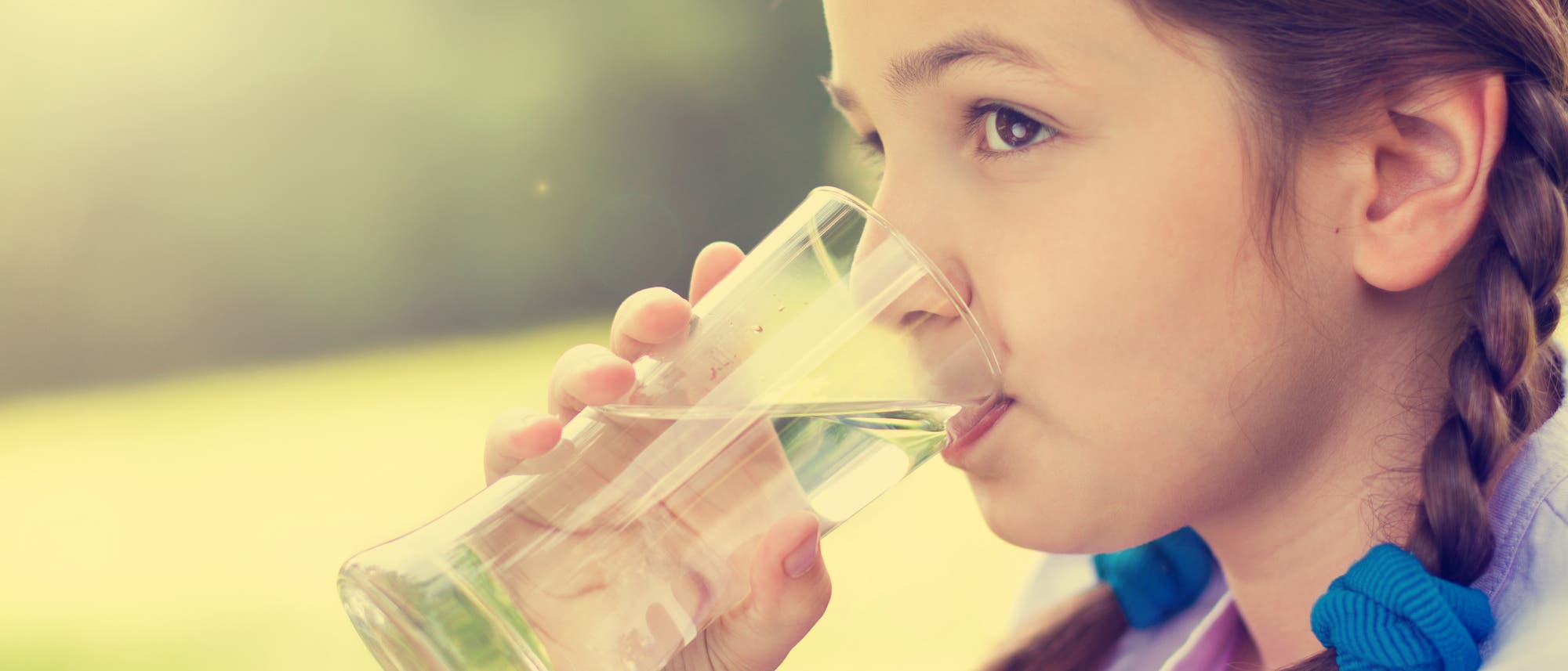 Ein Mädchen löscht seinen Durst mit einem Glas Wasser