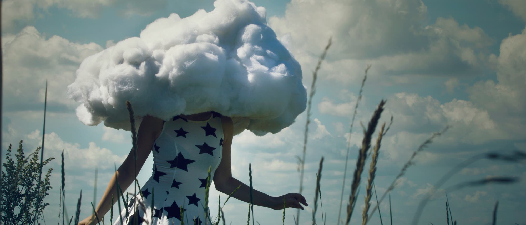 Eine Frau mit Wolkenkopf läuft durch ein Feld