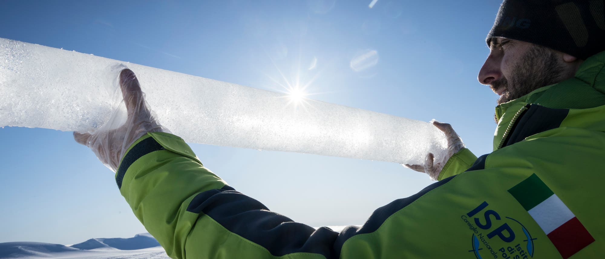 Ein Forscher hält einen Eisbohrkern in die Kamera