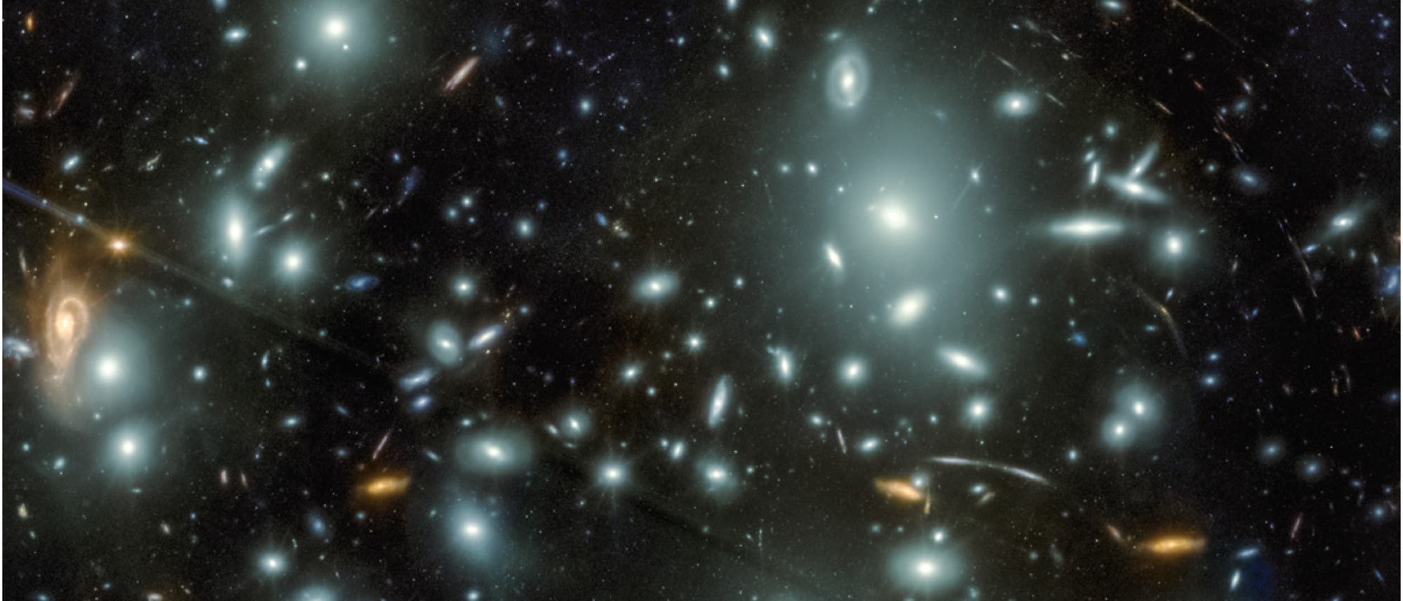 Ein astronomisches Bild zeigt eine Vielzahl von Galaxien in unterschiedlichen Formen und Farben, die &uuml;ber das gesamte Bild verteilt sind. Einige Galaxien erscheinen als helle, diffuse Lichtflecken, w&auml;hrend andere spiralf&ouml;rmige Strukturen aufweisen. Im Hintergrund sind zahlreiche kleinere Lichtpunkte sichtbar, die entfernte Sterne oder Galaxien darstellen. Die Bildunterschrift zeigt eine Skala von 10 Bogensekunden, die die Gr&ouml;&szlig;enverh&auml;ltnisse im Bild verdeutlicht. Das Bild veranschaulicht die Vielfalt und Weite des Universums.