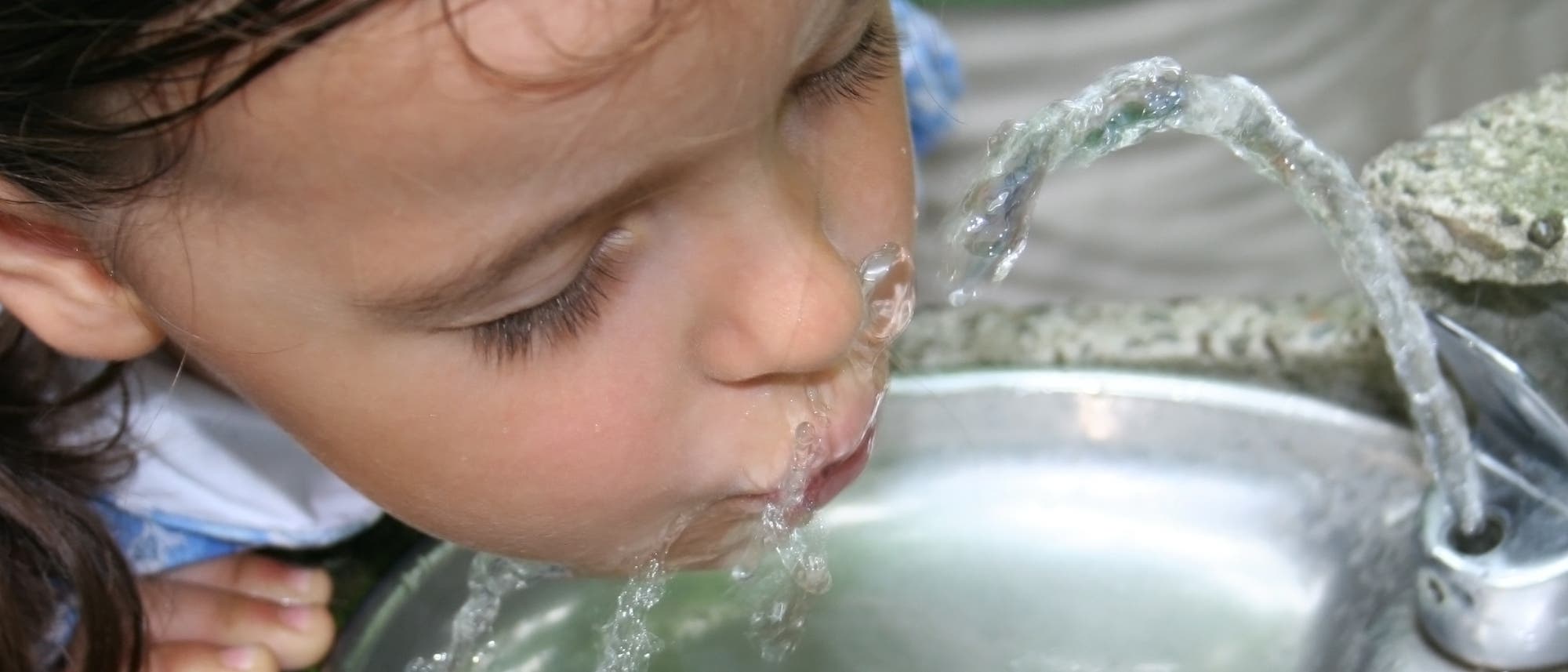 Mädchen trinkt aus einem anscheinend öffentlichen Trinkwasserbrunnen. Ob Eltern heutzutage so was noch erlauben würden?