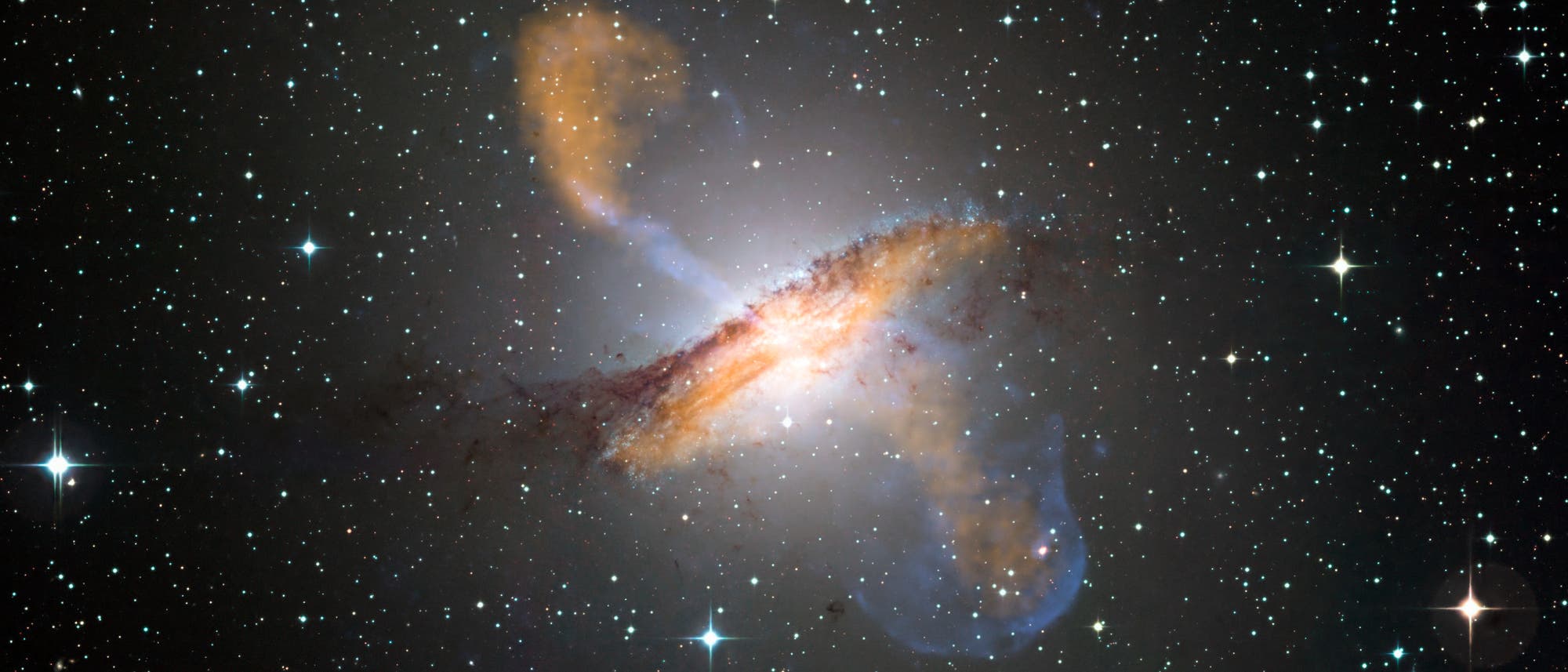 In der Mitte der Spiralgalaxie Centaurus A befindet sich ein Schwarzes Loch, das eng gebündelte Materiestrahlen (blau) aussendet, die nur durch Röntgenteleskope sichtbar werden. Die orange dargestellten Molekülwolken der Galaxie emittieren dagegen Licht im Submillimeterbereich.