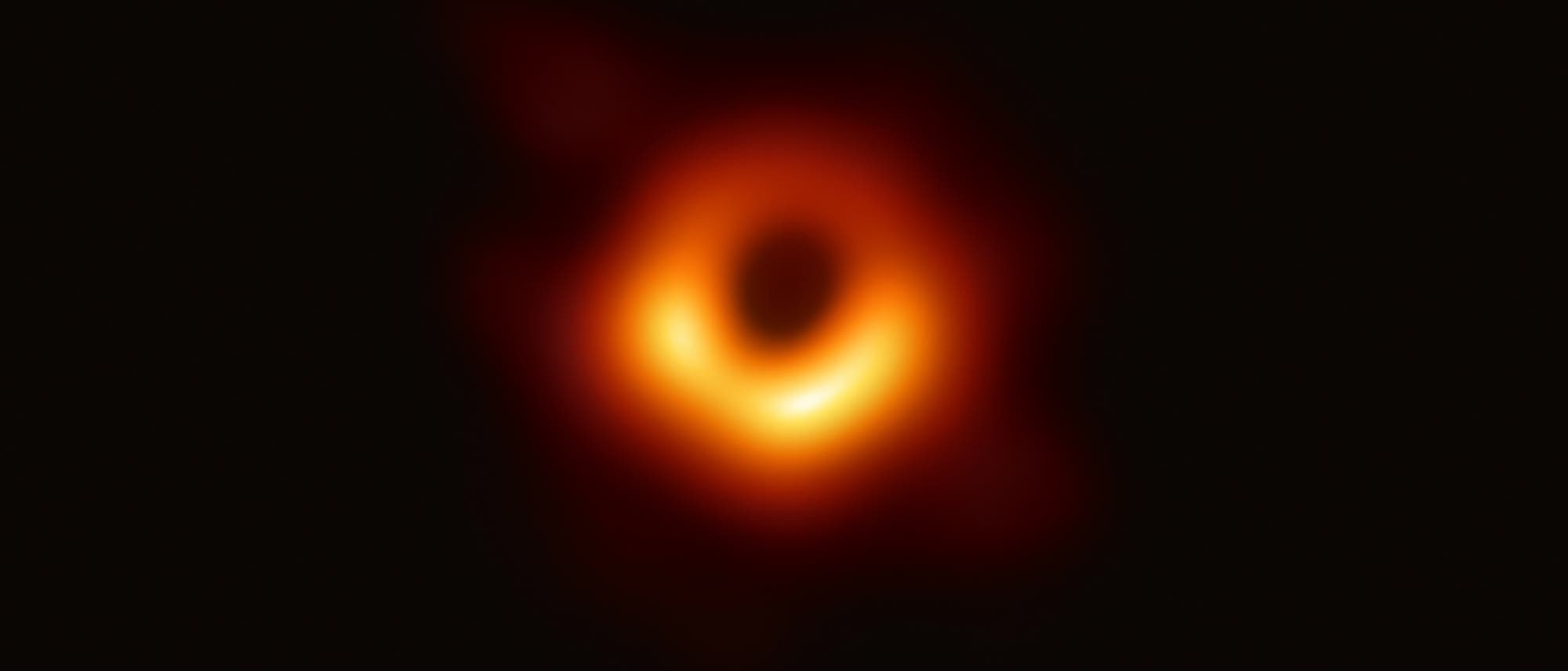 Ein verschwommenes, ringf&ouml;rmiges Bild eines Schwarzen Lochs, das von einem hellen, leuchtenden Ring aus Gas und Staub umgeben ist. Der Hintergrund ist dunkel, was den Kontrast zum leuchtenden Ring verst&auml;rkt. Dieses Bild zeigt das erste direkte visuelle Abbild eines Schwarzen Lochs, aufgenommen vom Event Horizon Telescope. Schl&uuml;sselw&ouml;rter: Schwarzes Loch, Event Horizon Telescope, Astronomie, leuchtender Ring.