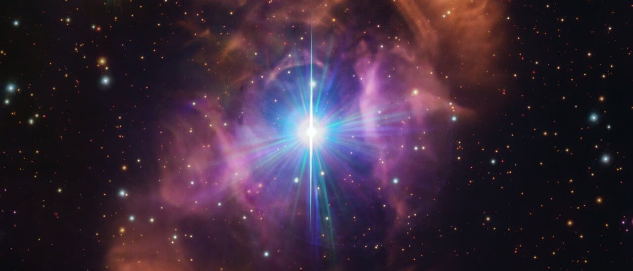 Diese Aufnahme im sichtbaren Licht des  VLT Survey Telescope zeigt im Zentrum einen hell leuchtenden Stern, der umgeben ist von einem farbigen kosmischen Nebel. Außerhalb des Nebels leuchten zahlreiche weitere Sterne in der Schwärze des Universums 