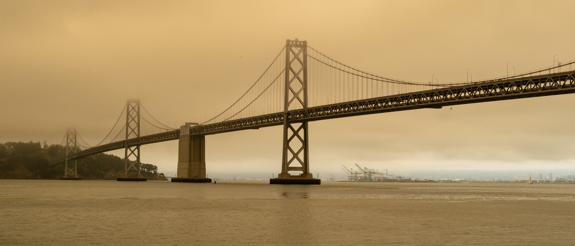 Die Bay Bridge in San Francisco umgeben von Smog durch nahe gelegene Waldbrände. Saubere Luft ist in der Ferne am Hafen von Oakland zu sehen.