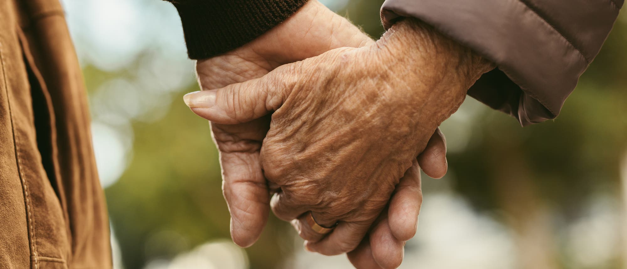 Zwei ältere Menschen halten sich an den Händen.