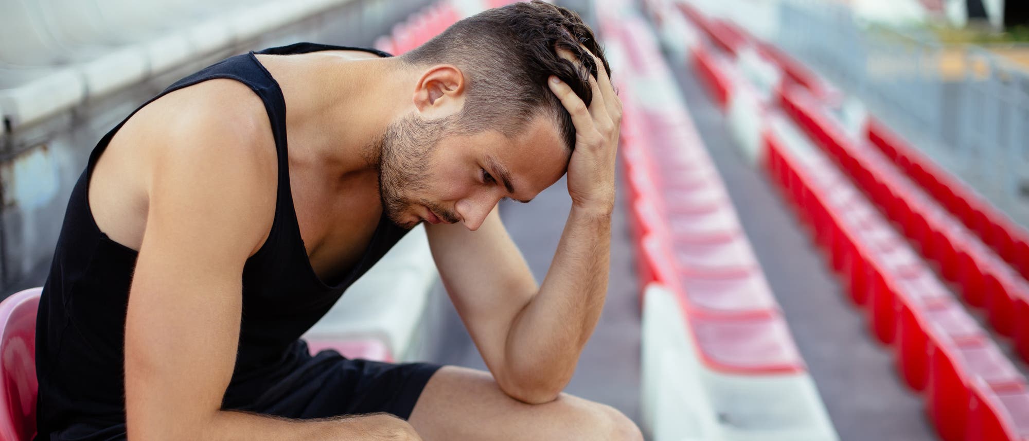 Deprimierter Sportler sitzt auf Stadionbank