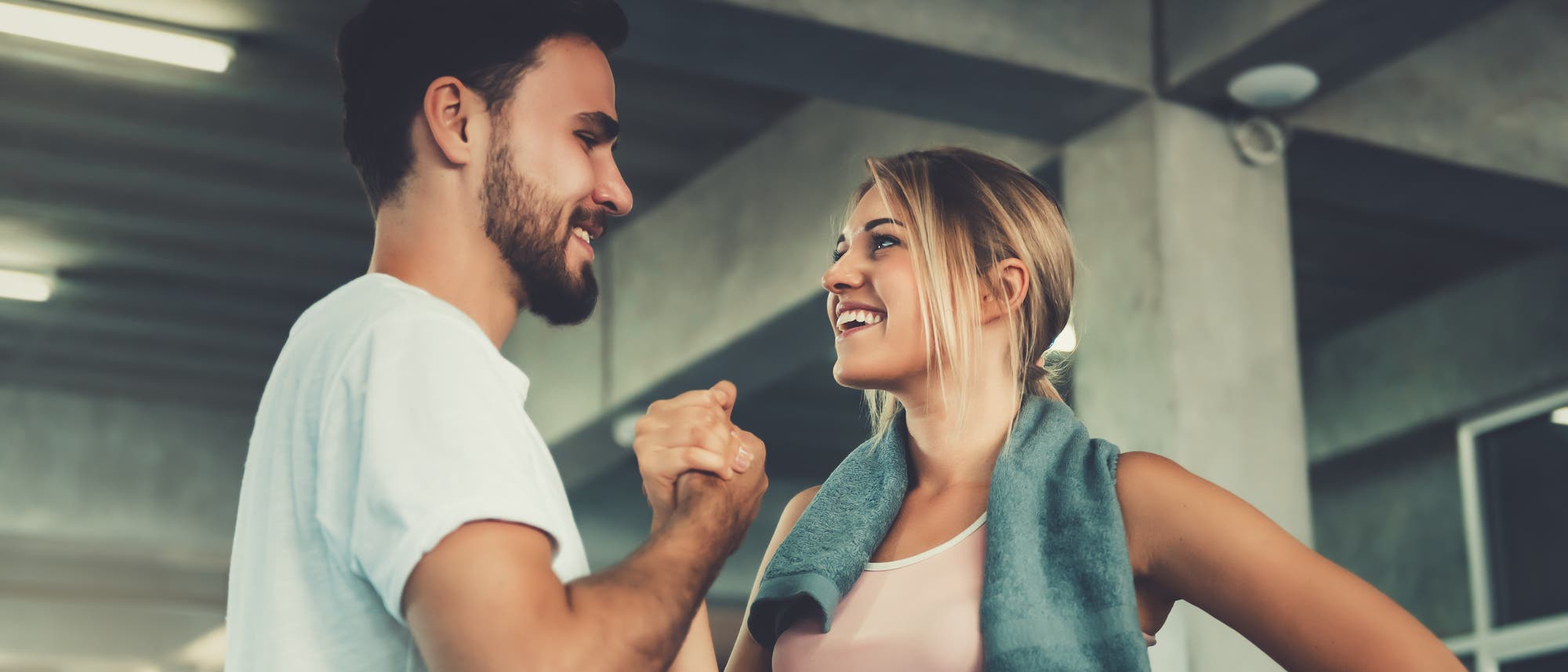 Eine Frau und ein Mann in Sportkleidung geben sich einen Handschlag und freuen sich.