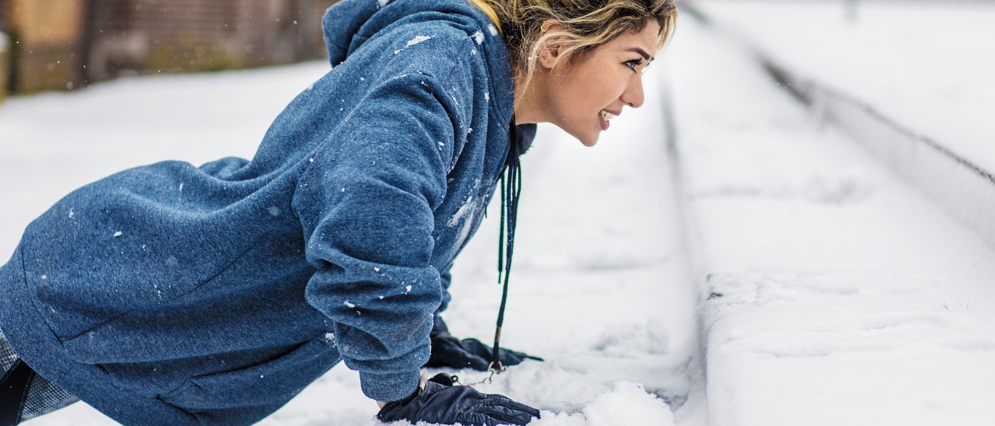 Eine Sportlerin macht im Schnee auf einer Treppe Liegestützen.