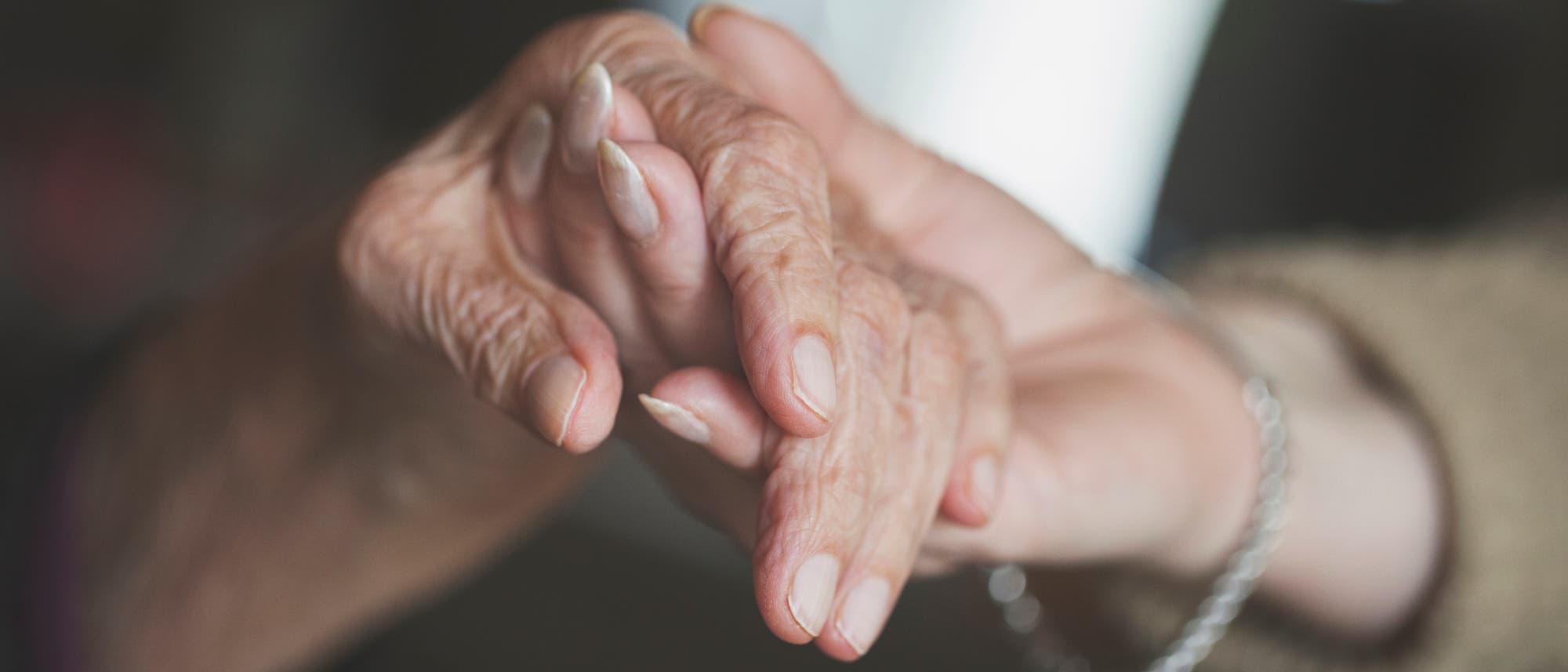 Hände eine älternen und einer jüngeren Frau, die sich gegenseitig halten