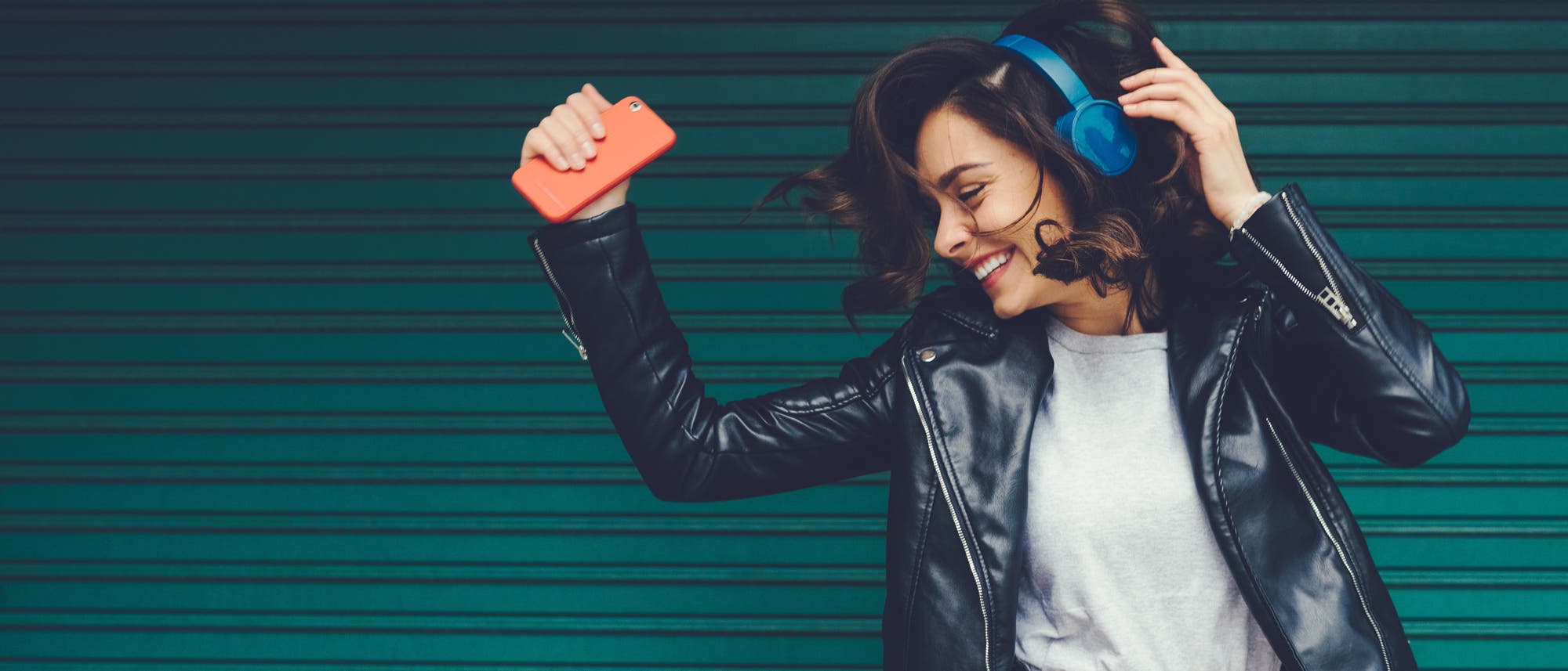 Frau mit Kopfhörer tanzt zur Musik aus ihrem Smartphone