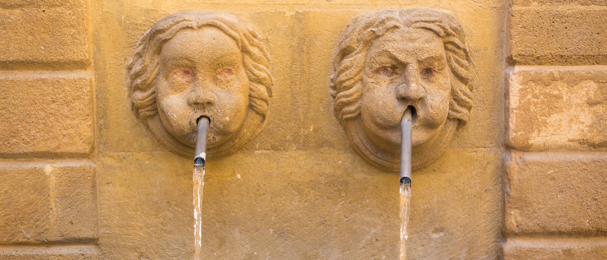 Zwei kuriose gesichtsförmige Wasserspeier speien Wasser.