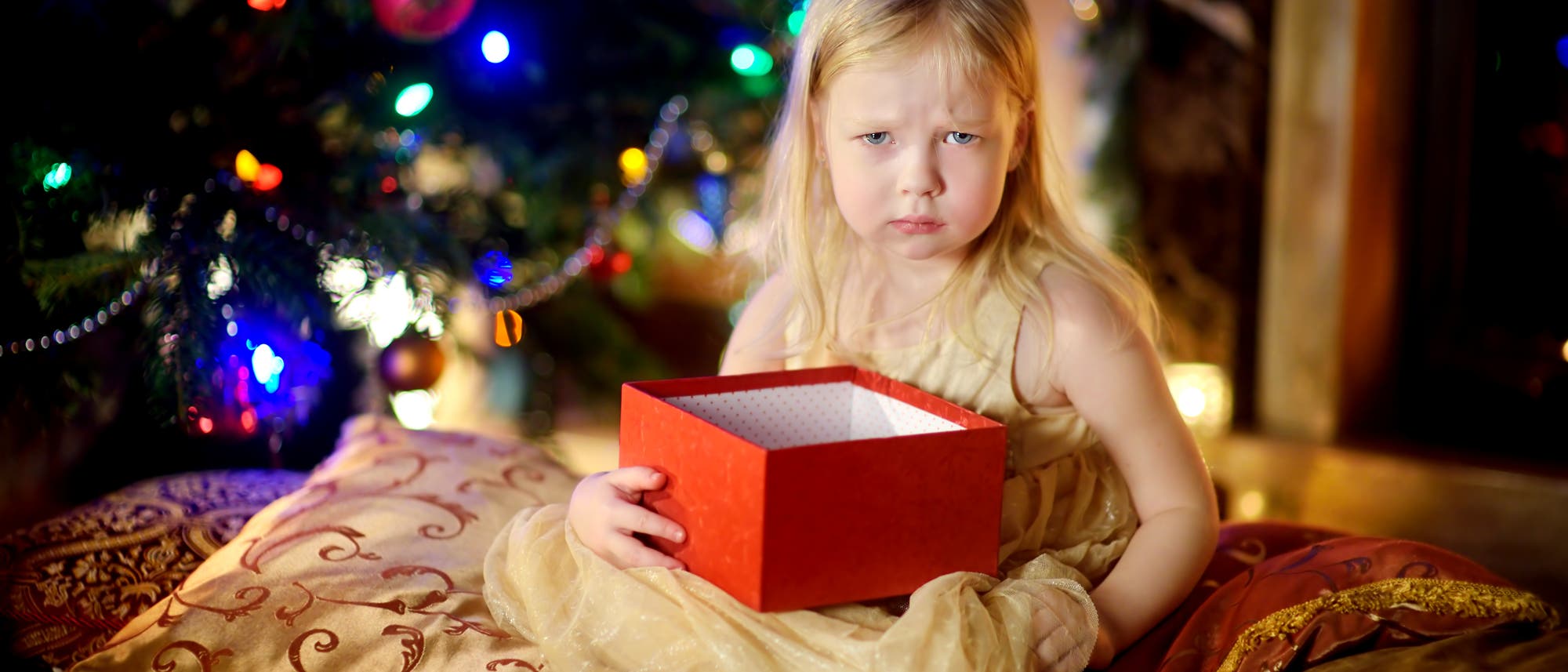 Ein kleines Mädchen ist unglücklich mit seinem Weihnachtsgeschenk