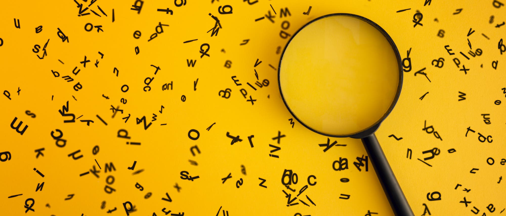 Ein schwarzes Vergrößerungsglas liegt auf einem gelben Hintergrund, umgeben von verstreuten schwarzen Buchstaben in verschiedenen Größen und Ausrichtungen. Das Bild vermittelt den Eindruck von Suche und Entdeckung, wobei der Fokus auf den Buchstaben liegt, die durch das Glas vergrößert erscheinen. Ein schwarzes Vergrößerungsglas liegt auf einem gelben Hintergrund, umgeben von verstreuten schwarzen Buchstaben in verschiedenen Größen und Ausrichtungen. Das Bild vermittelt den Eindruck von Suche und Entdeckung, wobei der Fokus auf den Buchstaben liegt, die durch das Glas vergrößert erscheinen.