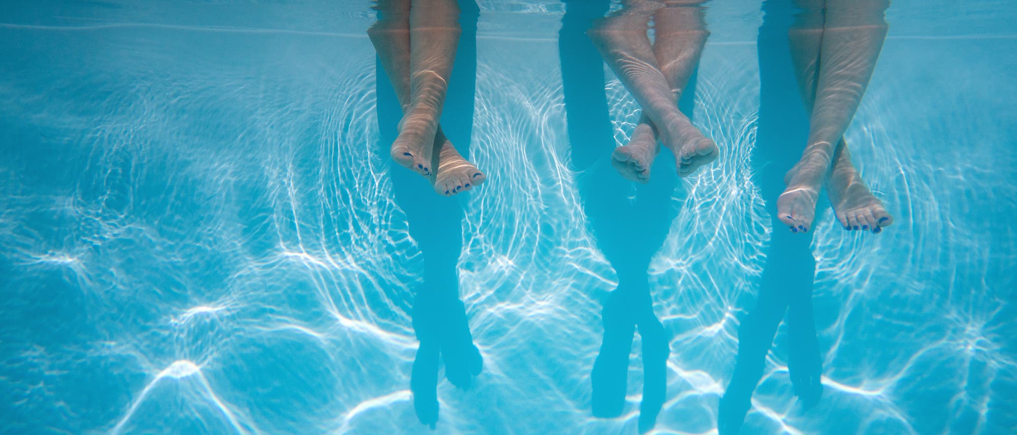 Beine baumeln in ein Schwimmbecken.