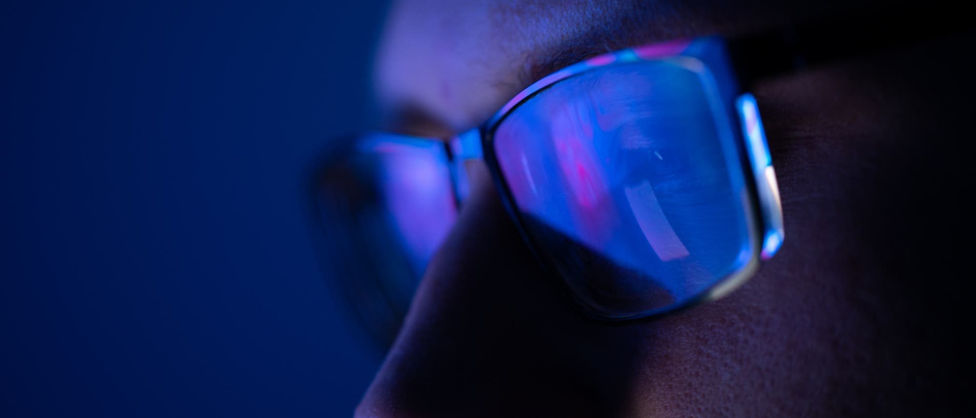 In einer Brille spiegelt sich blaues Licht eines Computermonitors