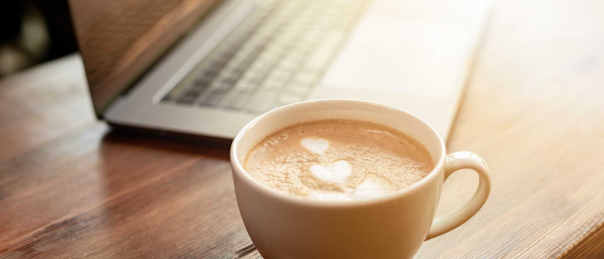Ein Milchkaffee steht vor einem Laptop