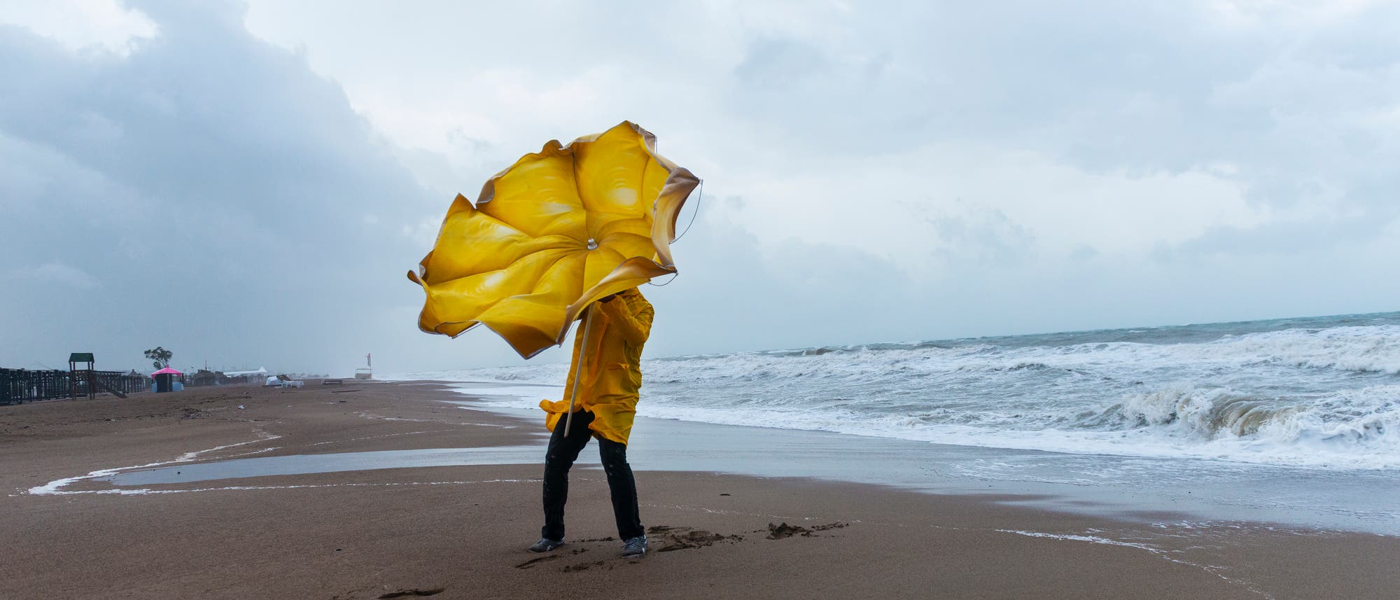 Eine Person läuft am Strand durch Regen und Sturm