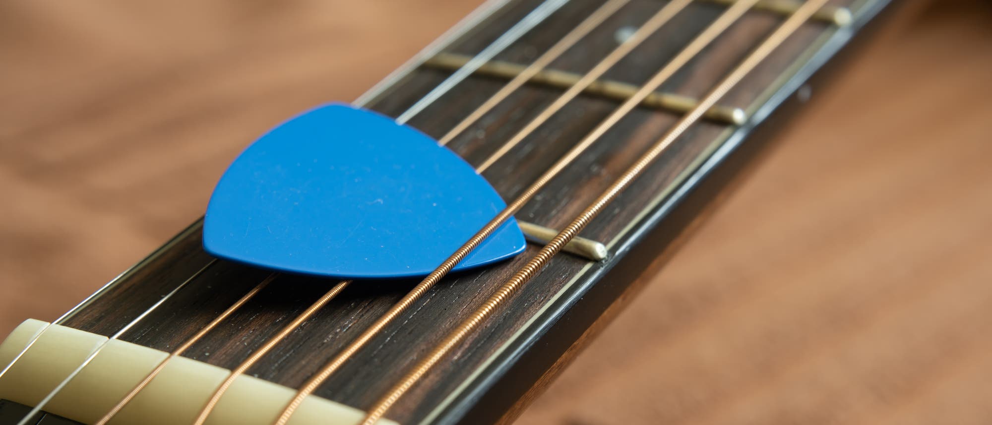 Gitarrenhals mit blauem Plektrum auf den Saiten.