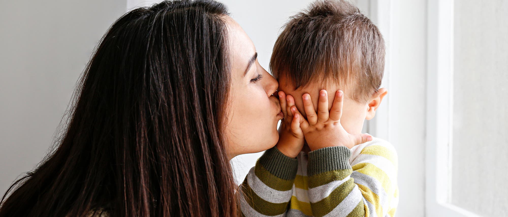 Mutter gibt weinendem Kind ein Küsschen