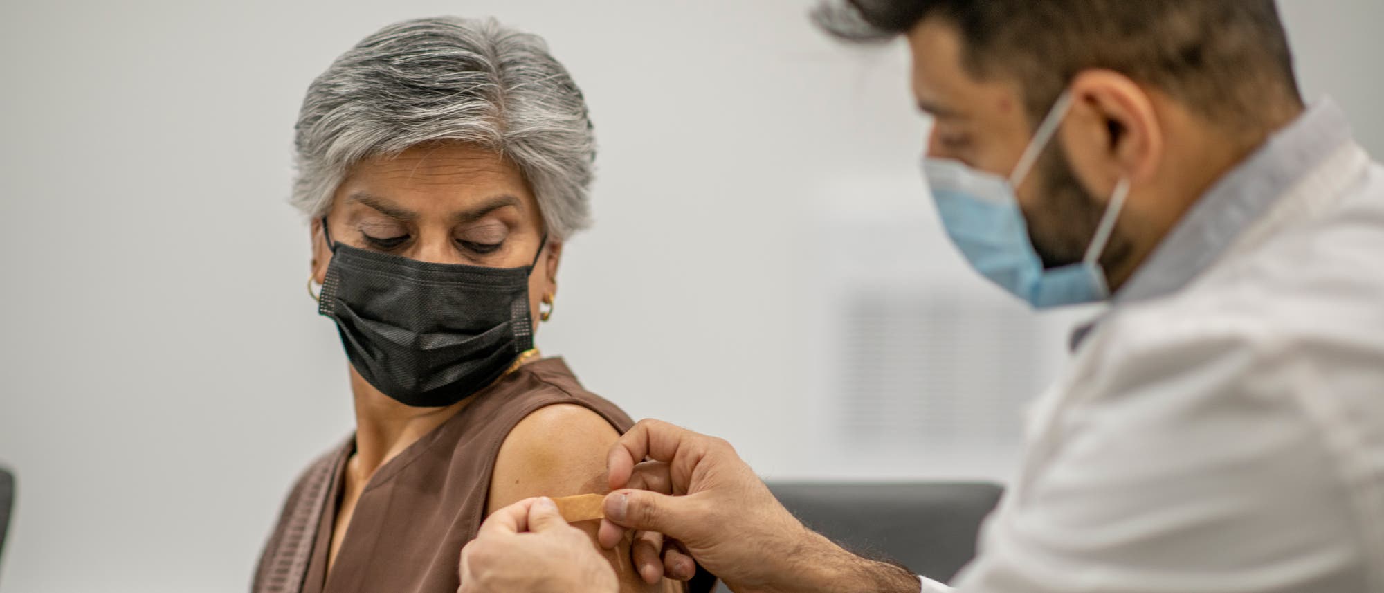 Eine Frau erhält nach der Impfung ein Pflaster auf die Einstichstelle.