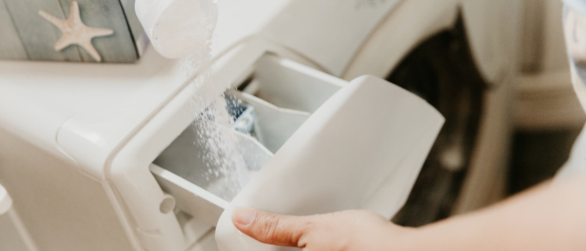 Waschpulver wird ins Waschmittelfach einer Waschmaschine gefüllt.