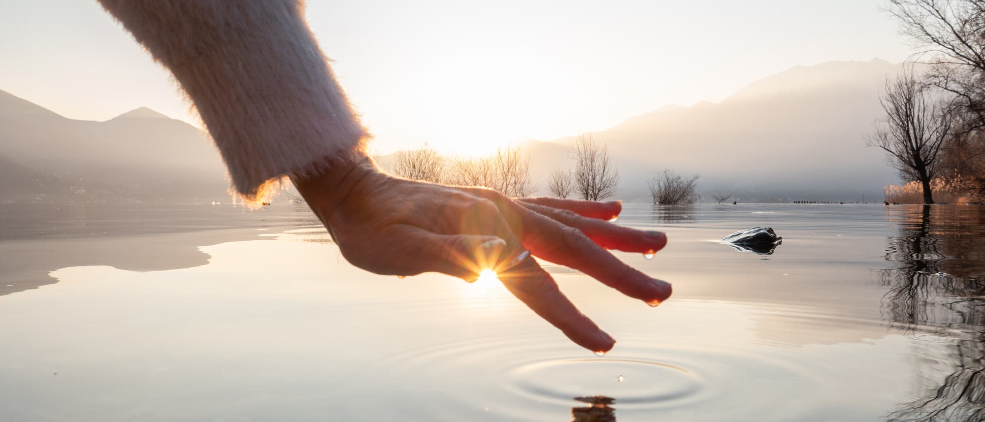 Hand berührt Oberfläche eines Sees
