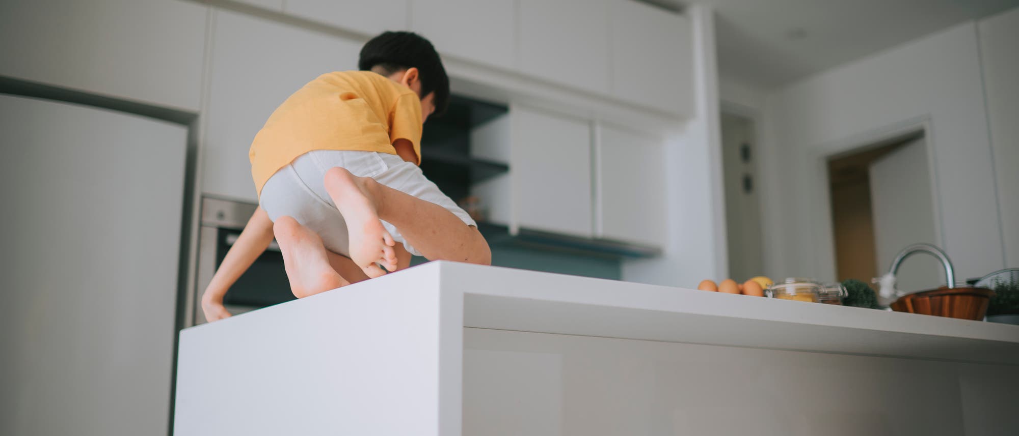 Junge klettert auf einer Küchenzeile herum