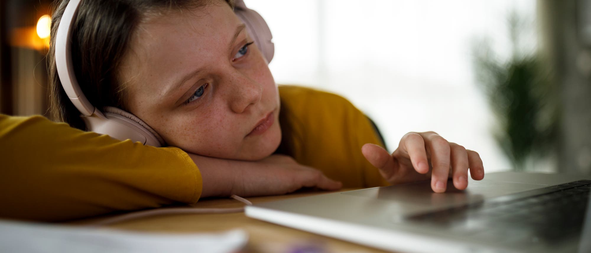 Ein Mädchen sitzt erschöpft vor dem Rechner