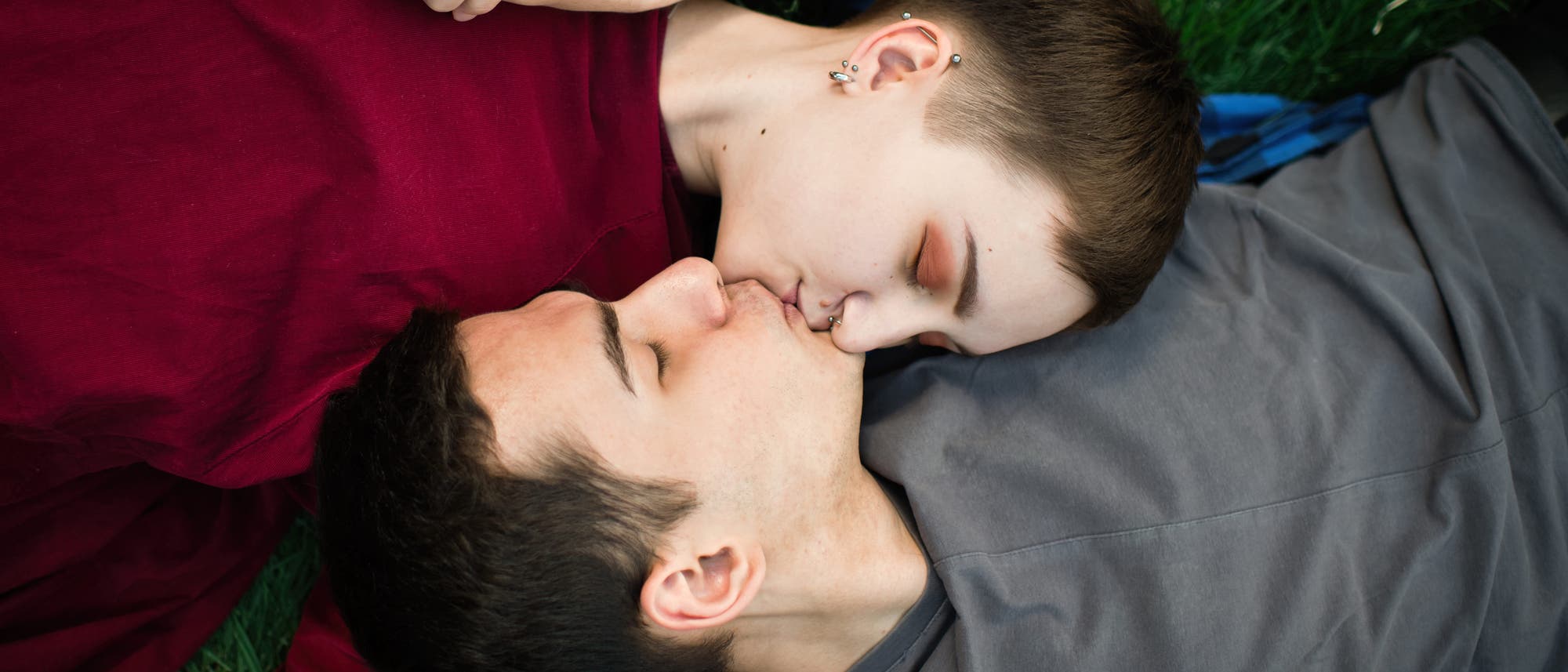 Mädchen und Junge im Teenageralter liegen auf einer Wiese und küssen sich  