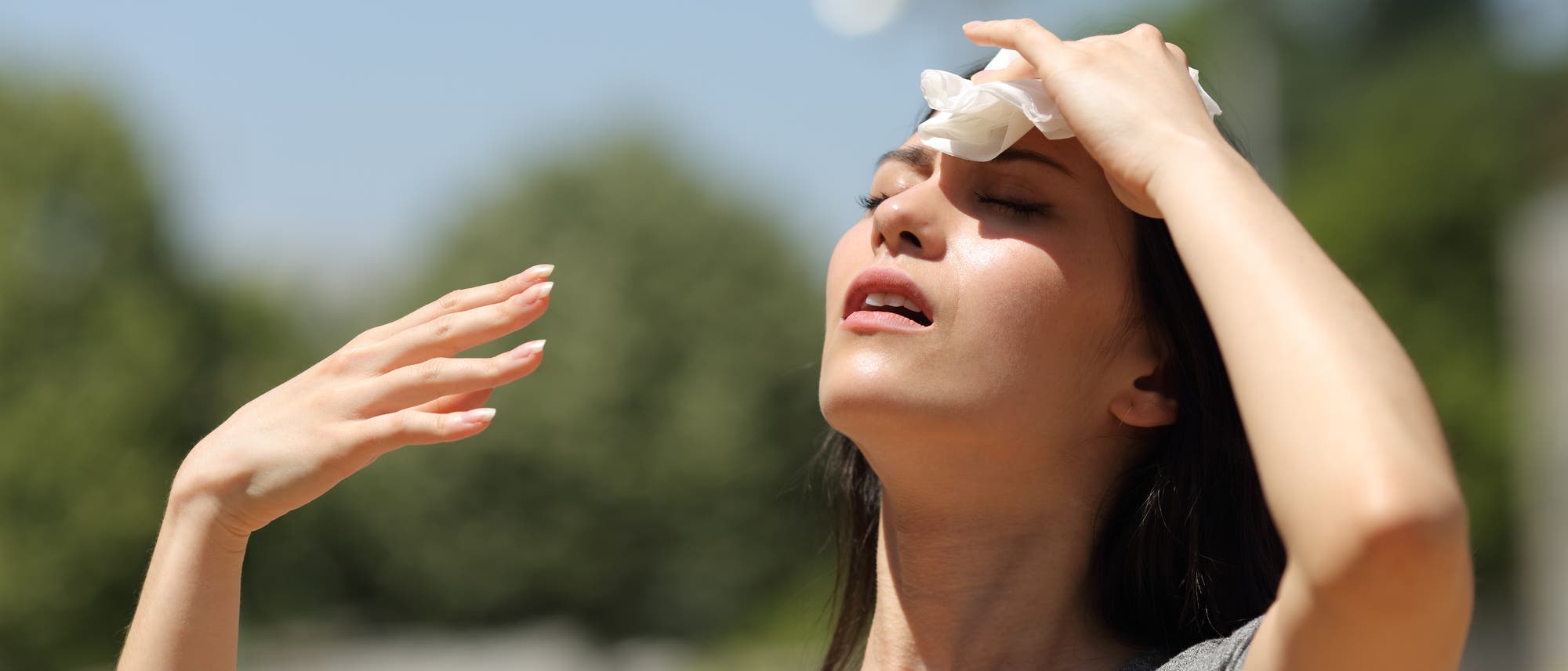 Eine Frau kühlt ihre Stirn an einem heißen Sommertag