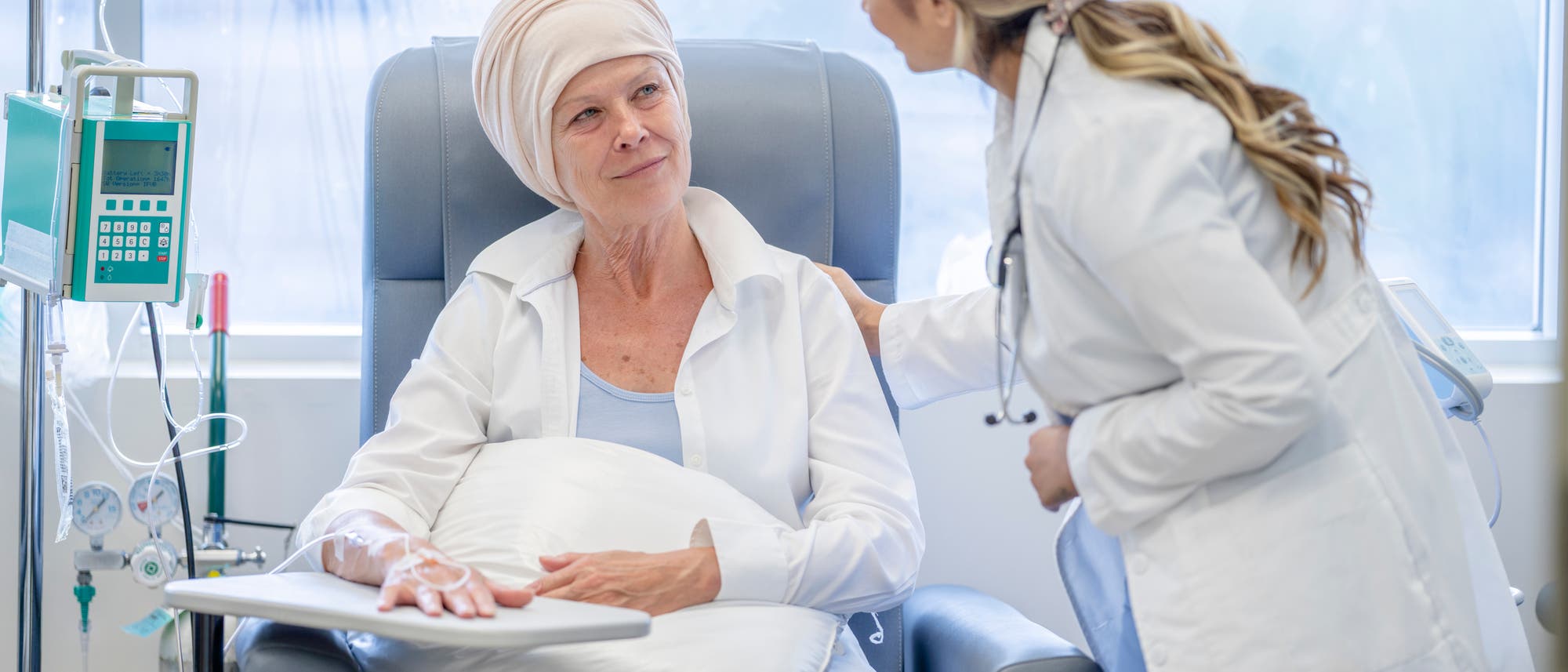 Eine Onkologin spricht mit eine Krebspatientin, die eine Chemotherapie erhält. Die Patientin hört aufmerksam zu.
