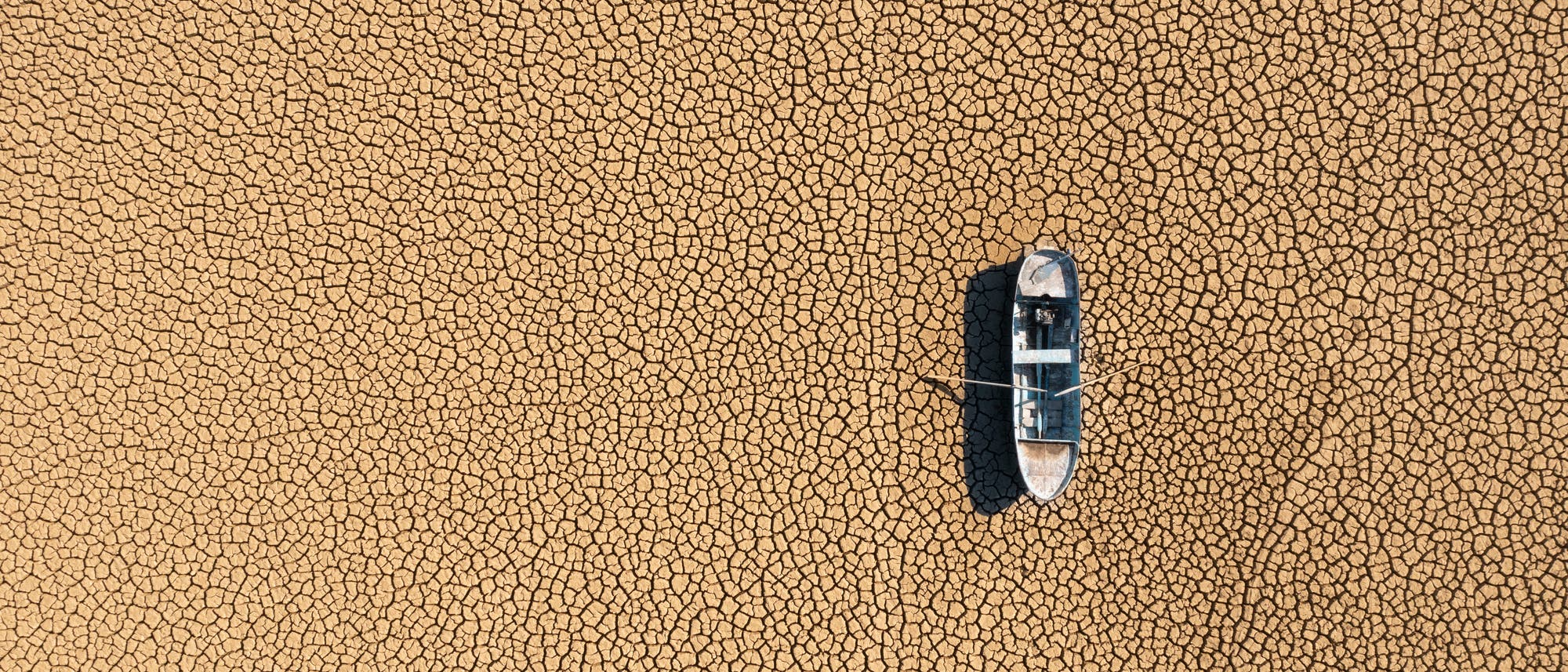 Ein Boot liegt auf einem rissigen, ausgetrockneten See