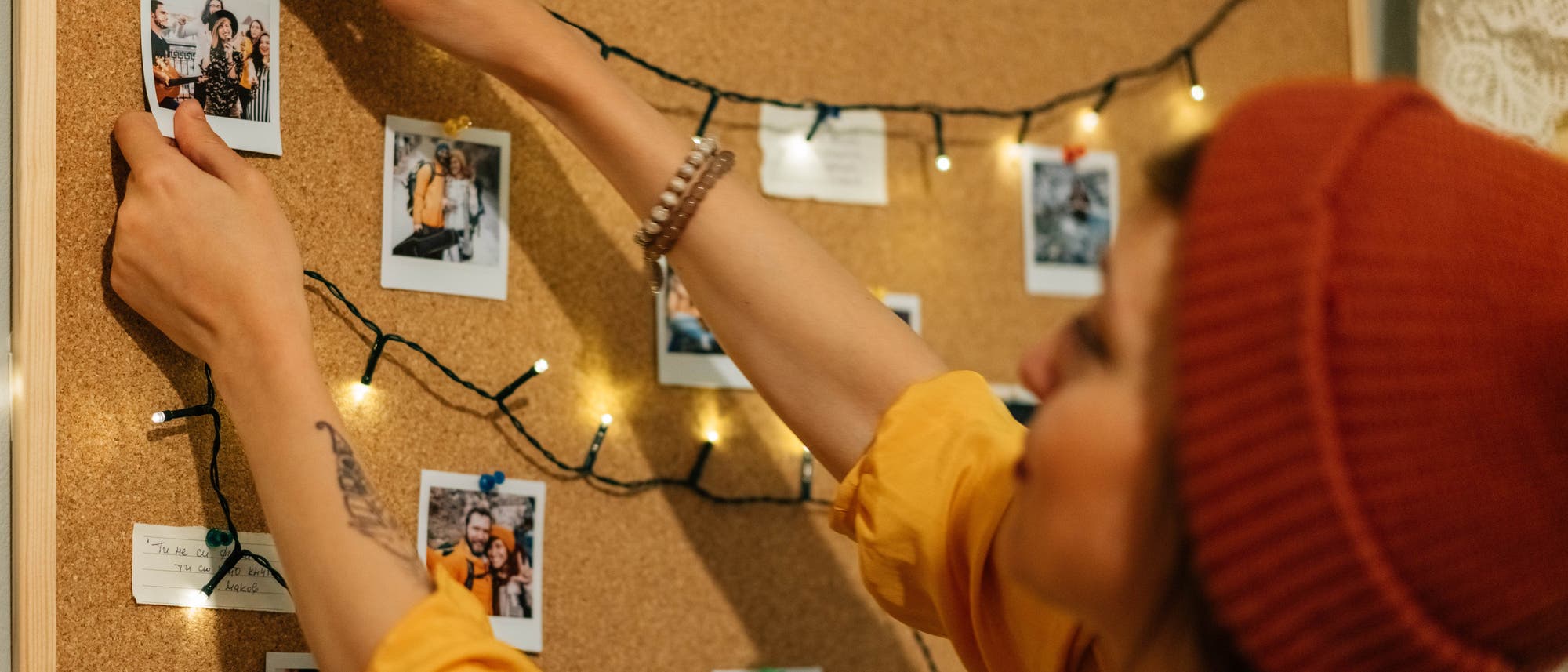 Eine junge Frau hängt Fotos an einer Pinnwand auf