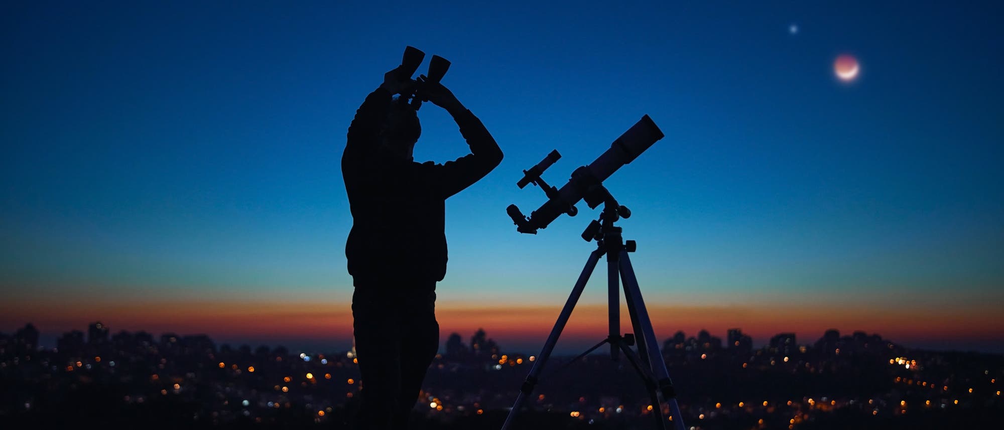 Silueta de una persona con binoculares sobre el fondo de un cielo oscuro.