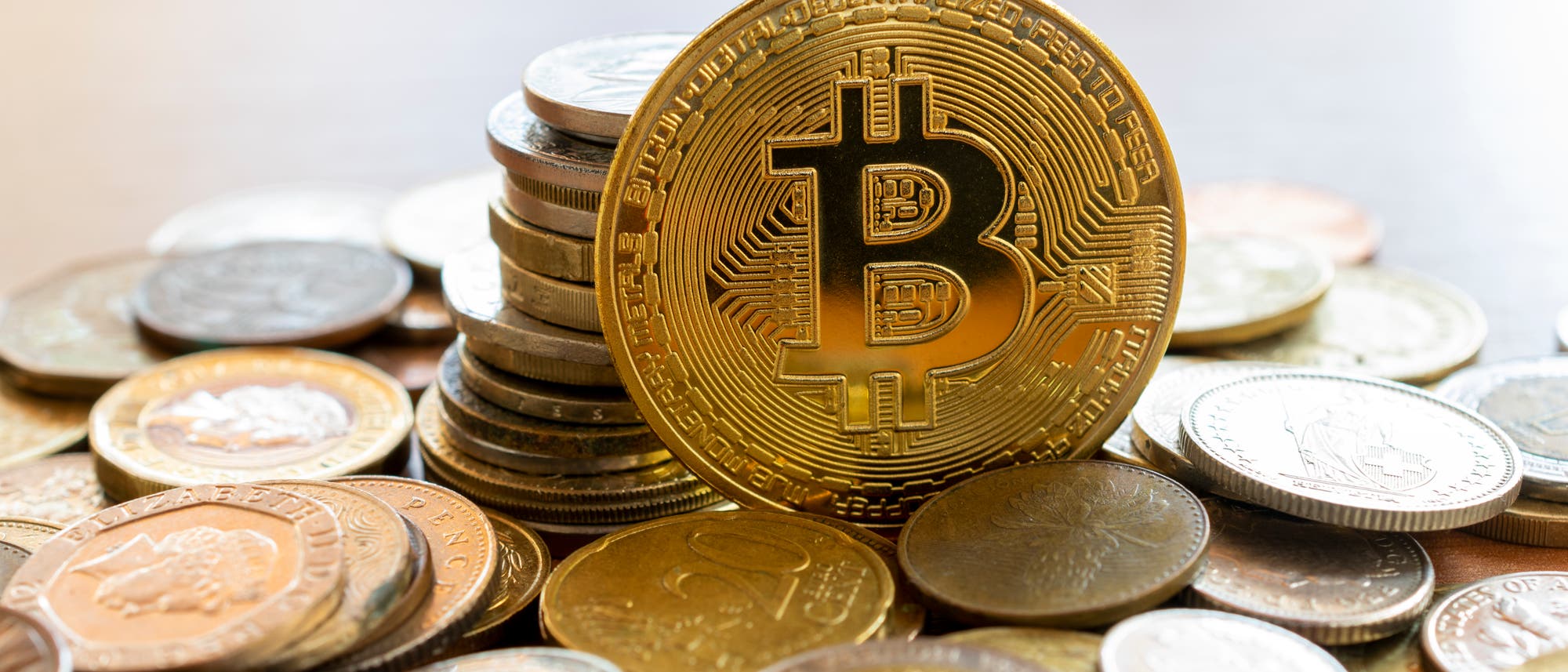 Ein Bitcoin liegt auf einem Haufen anderer Münzen