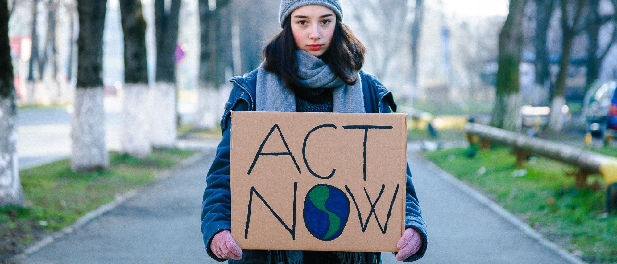 Junge Klimaaktivistin hält ein Schild mit der Aufschrift »Act Now« 