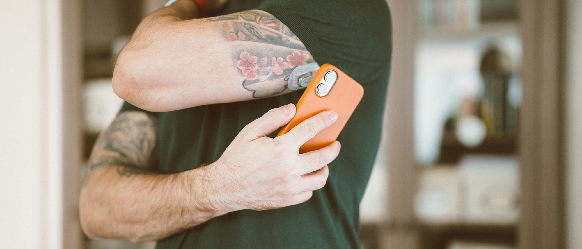 Mann hält sich ein Smartphone an den Oberarm, an welchem ein Sensor befestigt ist