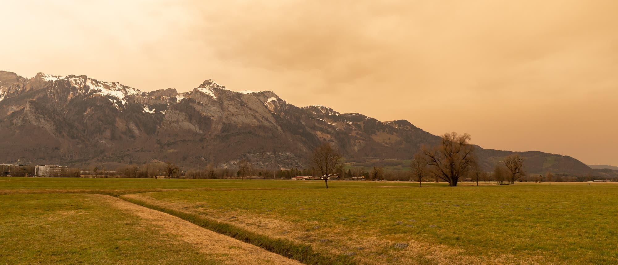 Saharastaub färbt den Himmel über dem Rheintal in Liechtenstein gelblich.