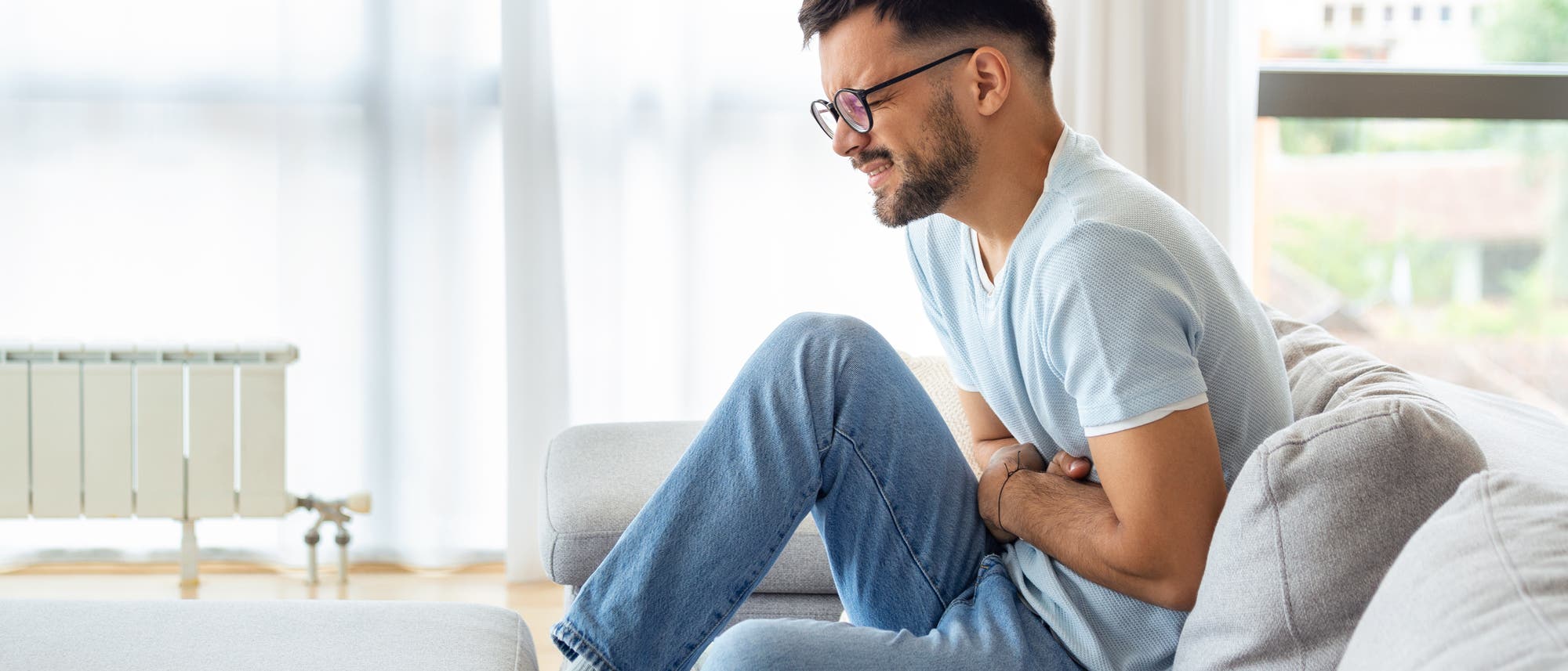 Mann hält sich den Bauch und krümmt sich vor Schmerzen Mann hält sich den Bauch und krümmt sich vor Schmerzen