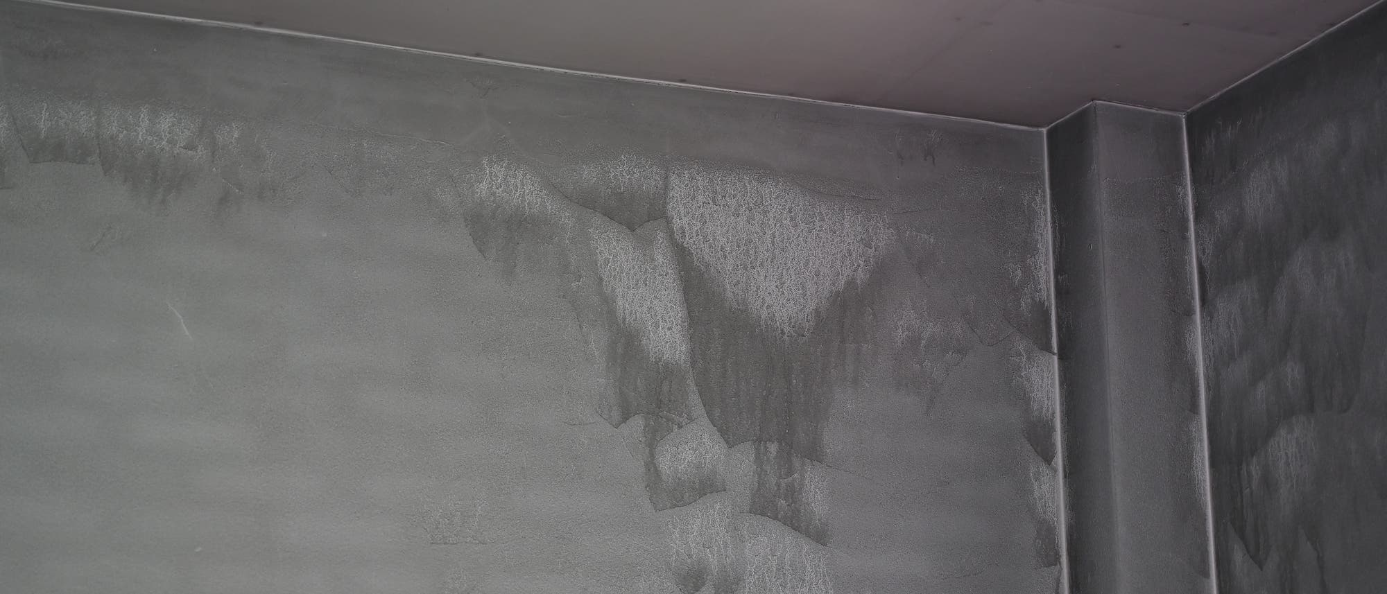 Eine ehemals weiße Wand zeigt starke Ablagerungen von schwarzem Staub