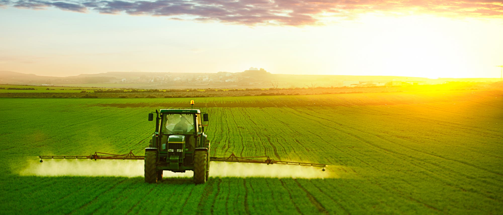 Ein Traktor versprüht Agrarchemikalien auf einem Feld.