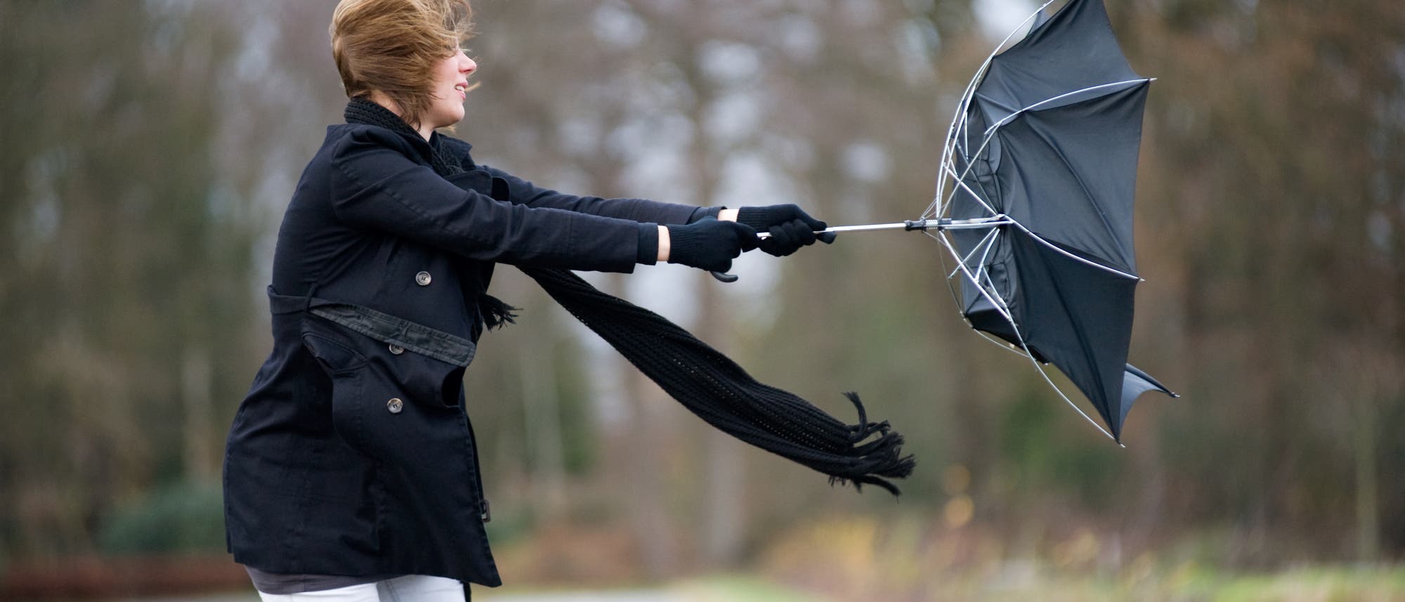 Frau kämpft mit umgeklapptem Regenschirm