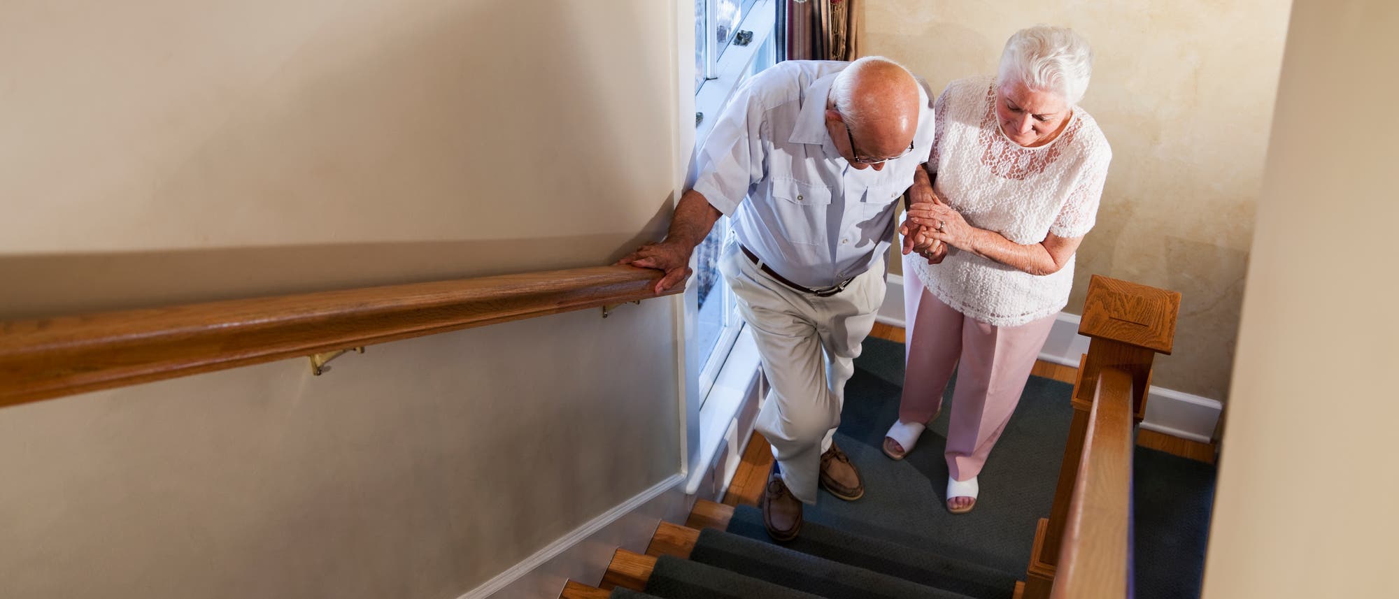 Eine ältere Dame hilft einem Mann die Treppe hinauf.