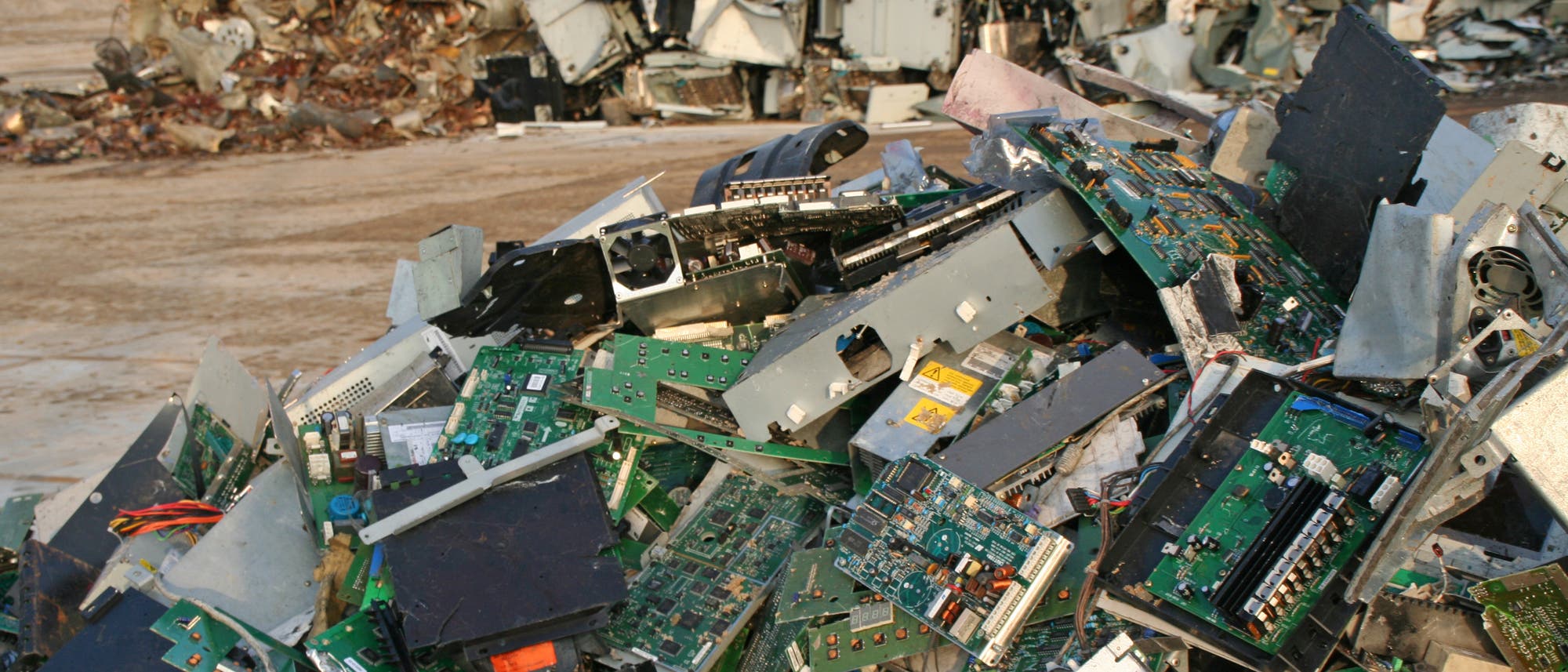 Ein ungeordneter Haufen aus Computerteilen liegt auf nackter Erde.