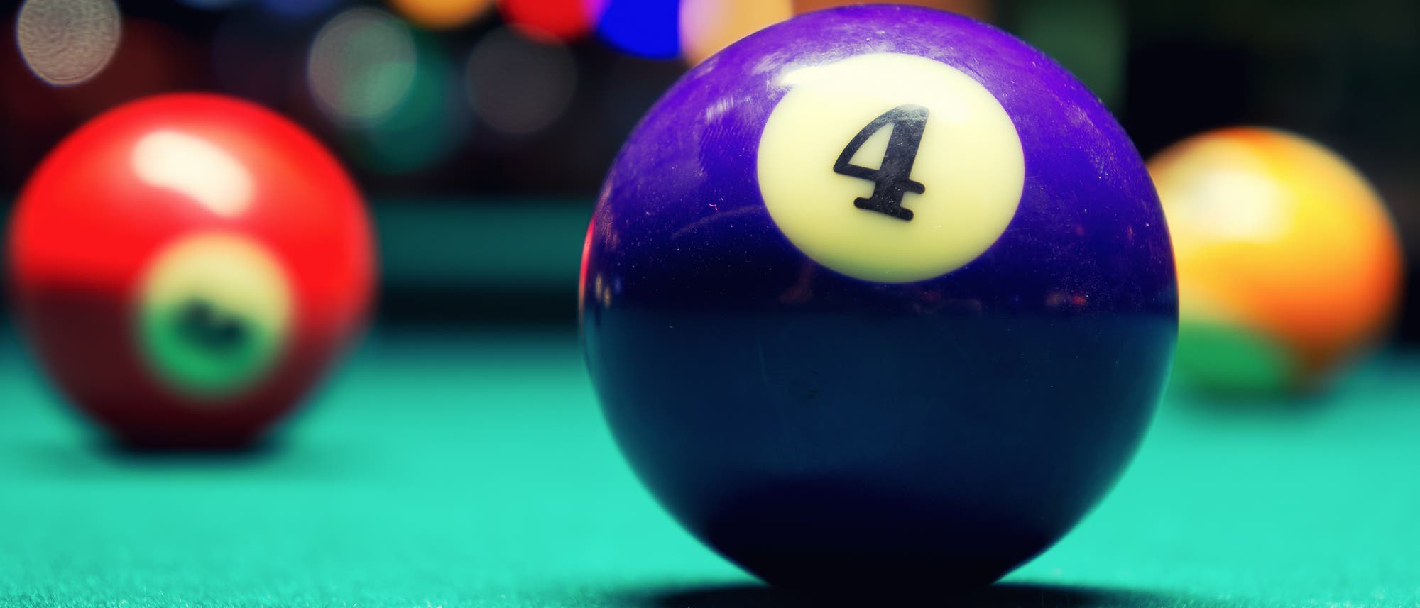 Foto eines Billiardtischs, auf dem die Kugel mit der Nummer Vier im Fokus ist